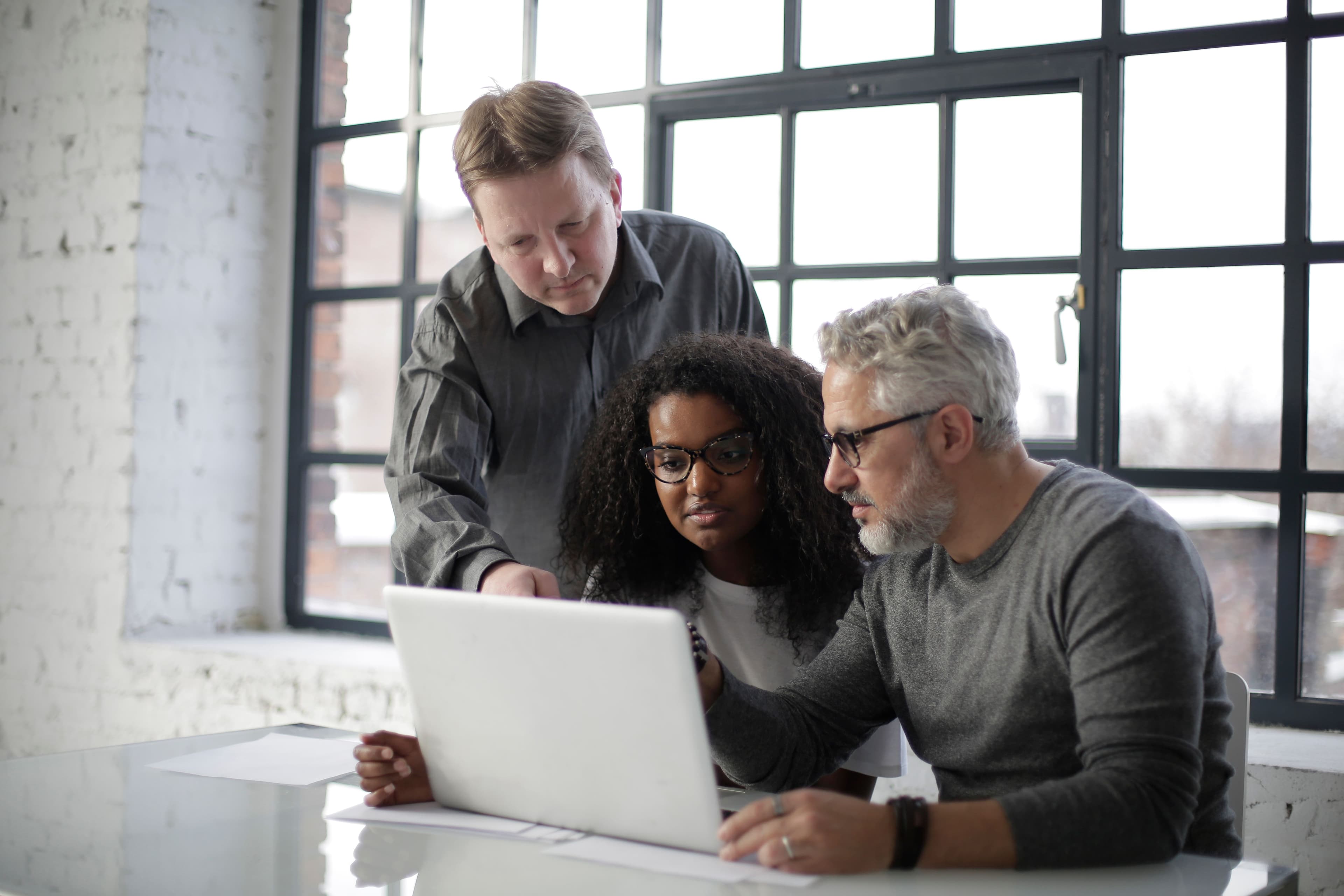 Illustrative team discussing a work process around a laptop